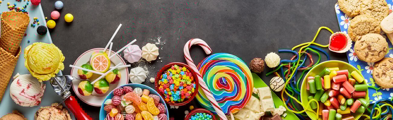 An assortment of colourful, festive sweets, ice-cream and candy in a panoramic orientation with a dark background and copy space.; Shutterstock ID 711008170